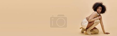 Banner eines afrikanisch-amerikanischen Models in stylischem Pastellkostüm und schenkelhohen Stiefeln posiert auf beige