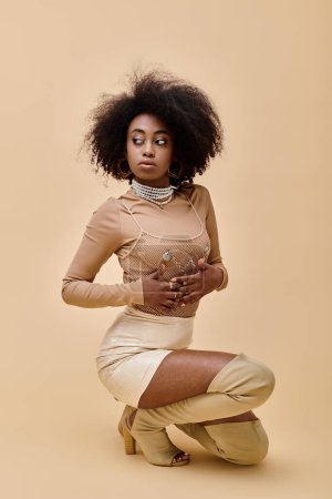 confident african american model in stylish outfit and thigh-high boots posing on beige backdrop