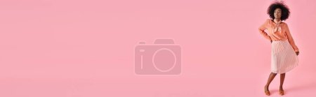 Photo for Elegant african american woman in peach blouse and midi skirt posing on pastel pink backdrop, banner - Royalty Free Image