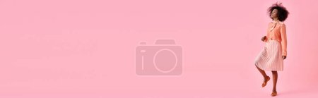 Photo for Curly african american woman in peach blouse and midi skirt posing on pastel pink background, banner - Royalty Free Image