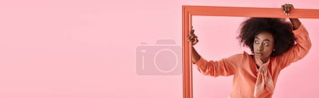 Photo for Banner, african american woman in peach fuzz blouse and neck scarf posing in frame on pink backdrop - Royalty Free Image