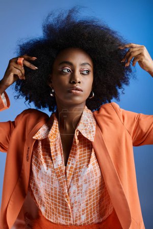 Téléchargez les photos : Jeune femme afro-américaine en tenue peach fuzz avec blazer posant sur fond bleu dégradé - en image libre de droit