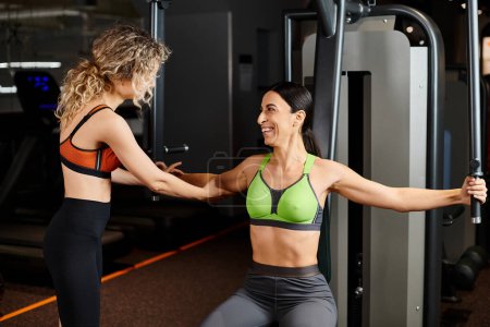 Photo for Merry female coach explaining to her good looking jolly client how to use chest press machine - Royalty Free Image