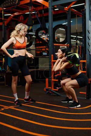 gut aussehende sportliche Frau und ihre athletische Trainerin beim Training mit Powerbag im Fitnessstudio