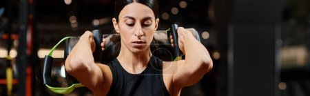 Foto de Hermosa mujer atlética con cabello moreno ejercitando activamente con bolsa de energía en el gimnasio, pancarta - Imagen libre de derechos
