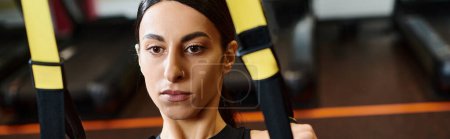 Photo for Energetic woman with brunette hair in comfy sportwear using pull ups equipment in gym, banner - Royalty Free Image