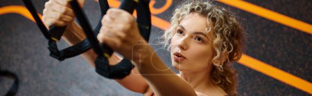 Foto de Mujer atractiva en ropa deportiva cómoda haciendo ejercicio con equipos pull ups mientras está en el gimnasio, pancarta - Imagen libre de derechos