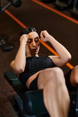athletisch gut aussehende Frau mit brünetten Haaren in bequemer Sportbekleidung Pumppresse im Fitnessstudio