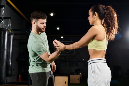 A male trainer teaches self-defense techniques to a woman, their movements flowing in harmony on the gym floor.