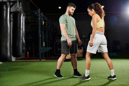 A male trainer teaches self-defense techniques to a woman in a gym setting.