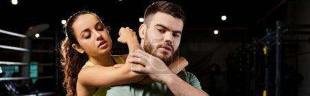 Un entrenador masculino demuestra técnicas de autodefensa a una mujer en un gimnasio, mostrando fuerza y coordinación.