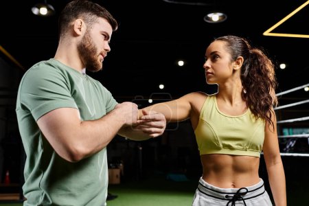 A male trainer teaches self-defense techniques to a woman in a gym.