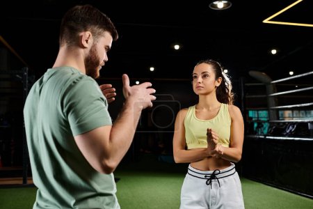 A male trainer demonstrates self-defense techniques to a woman in a gym, focusing on empowerment and skill-building.