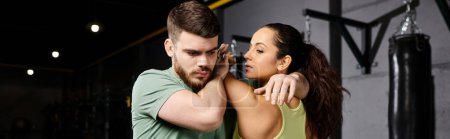 Ein männlicher Trainer bringt einer Frau in einem Fitnessstudio Selbstverteidigungstechniken bei.