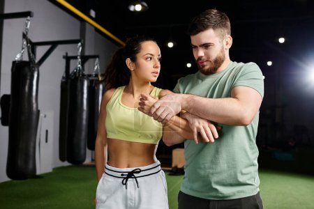 A male trainer teaches self-defense techniques to a woman in a gym, as they practice moves and build confidence.