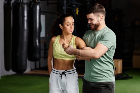 A male trainer demonstrates self-defense techniques to a woman in a gym setting, emphasizing safety and empowerment.