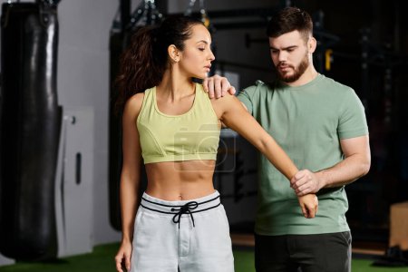 Ein männlicher Trainer demonstriert einer Frau in einem Fitnessstudio Selbstverteidigungstechniken und zeigt Einheit und Stärkung durch Fitness.