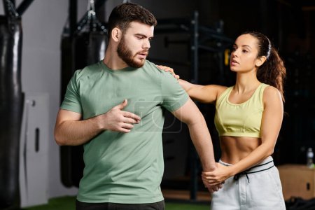 Un entrenador masculino está instruyendo a una mujer en técnicas de autodefensa en un entorno de gimnasio, centrado y determinado.