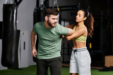 A male trainer is skillfully teaching self-defense techniques to a woman in a modern gym filled with fitness equipment.