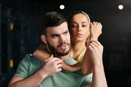 Téléchargez les photos : Un homme, un entraîneur d'auto-défense, tient une femme dans ses bras, démontrant une technique dans un cadre de gymnastique. - en image libre de droit