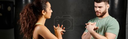 Ein männlicher Trainer bringt einer Frau im Fitnessstudio nebeneinander stehende Selbstverteidigungstechniken bei.