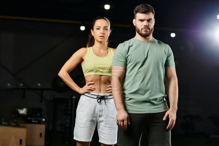 A male trainer is teaching self-defense techniques to a woman in a gym, as they stand next to each other.