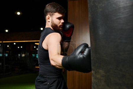 A stylish man with a beard, wearing a black tank top and boxing gloves, is seen punching a bag in a gym.
