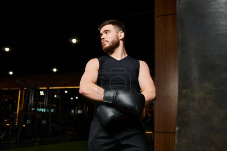 Hombre guapo con barba usando guantes de boxeo, lanzando potentes golpes a un saco de boxeo en un gimnasio.