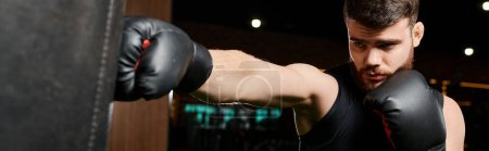 Un hombre barbudo con guantes de boxeo entrega un potente puñetazo a un saco de boxeo en un gimnasio.
