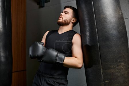 A handsome man with a beard wearing boxing gloves, intensely punching a bag in a gym.