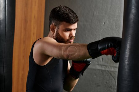 A handsome man with a beard wearing boxing gloves, punching a bag in the gym.