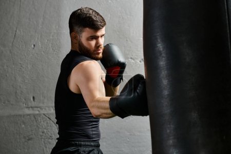Un hombre guapo con barba, con una camiseta negra y guantes de boxeo, practica sus golpes en una bolsa pesada en un gimnasio.