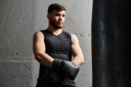 Téléchargez les photos : Beau barbu boxe homme, debout à côté d'un sac de boxe dans une salle de gym. - en image libre de droit