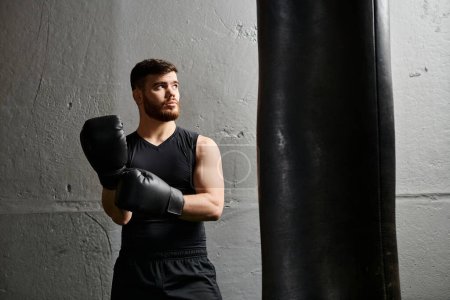 A handsome man with a beard stands next to a punching bag in a gym, practicing boxing.