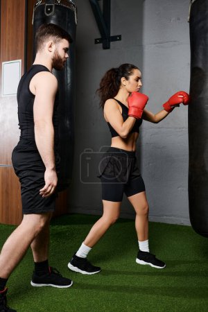 A male trainer guides a brunette sportswoman in active wear as they spar in a boxing ring.