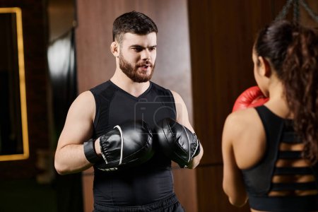 A male trainer and a brunette sportswoman boxing in a gym, showcasing strength and teamwork.