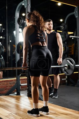 Ein männlicher Personal Trainer führt eine brünette Sportlerin durch Übungen im Fitnessstudio und konzentriert sich dabei auf Kraft und Ausdauer.