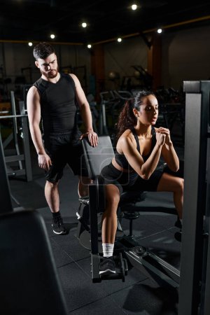 Ein Personal Trainer arbeitet mit einer brünetten Sportlerin in einem Fitnessstudio und konzentriert sich auf Kraft und Konditionierung.