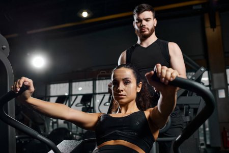 A male trainer motivates a brunette sportswoman during a workout session in the gym.
