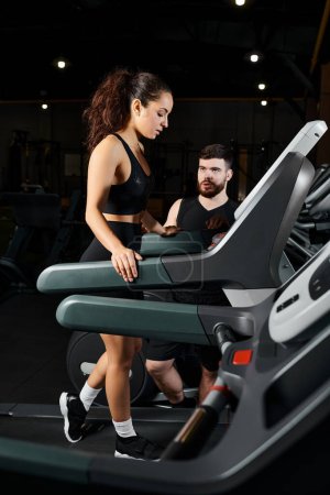 A male personal trainer and a brunette sportswoman are energetically running on a treadmill in a gym.
