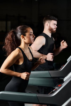 Ein Personal Trainer und eine brünette Sportlerin laufen auf Laufbändern in einem Fitnessstudio, halten Schritt und stoßen an ihre Grenzen.