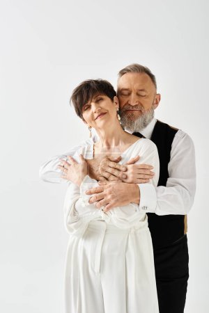 A middle-aged bride and groom, in wedding gowns, lovingly embrace each other in a studio setting, celebrating their special day.