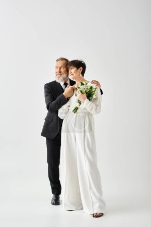 Foto de Novia y novio de mediana edad en traje de novia posan apasionadamente, irradiando alegría y amor en un entorno de estudio. - Imagen libre de derechos