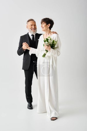 A middle-aged bride and groom in wedding attire celebrate their special day in a studio setting.