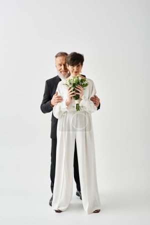 A middle aged bride and groom in wedding gowns celebrate their special day together in a studio setting.