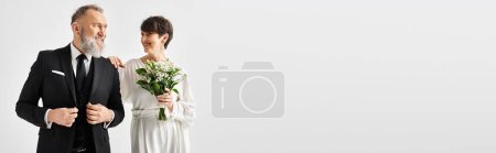 Téléchargez les photos : Une mariée d'âge moyen et marié en tenue de mariage, célébrant leur journée spéciale dans un cadre élégant studio. - en image libre de droit
