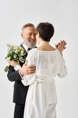 A middle aged man in a tuxedo wrapped in a warm embrace with a woman in a white wedding dress, celebrating their special day.