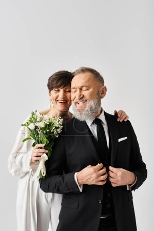 A middle-aged bride and groom in wedding gowns joyfully hugging each other, celebrating their special day in a studio setting.