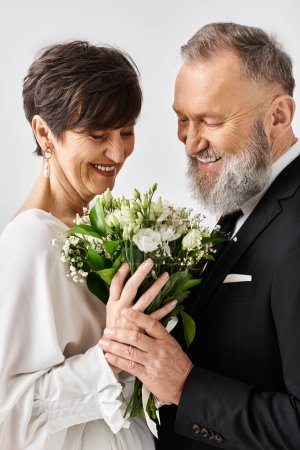 Téléchargez les photos : Une mariée d'âge moyen et marié en tenue de mariage s'embrassent amoureusement dans un cadre de studio. - en image libre de droit