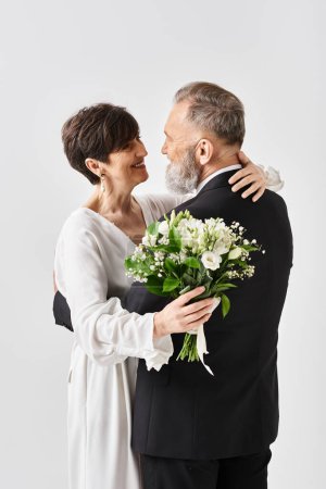 A middle-aged bride and groom in wedding gowns embracing each other, celebrating their special day in a studio setting.
